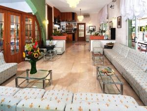 Hotel Saint Tropez SPA & Restaurant في ليدو دي سافيو: غرفة معيشة كبيرة مع الأرائك والطاولات والورود