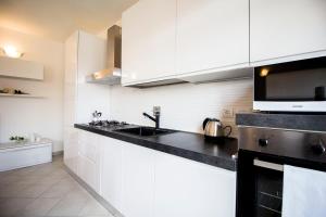 uma cozinha com armários brancos e um balcão preto em InnPisaRentals - Charme Pisa Toscana 2 em Pisa