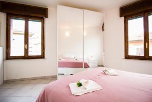 um quarto com uma cama rosa e 2 janelas em InnPisaRentals - Charme Pisa Toscana 2 em Pisa