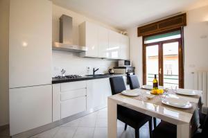 a kitchen with white cabinets and a table with chairs at InnPisaRentals - Charme Pisa Toscana 2 in Pisa