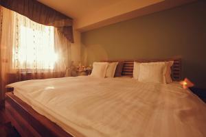 a large white bed in a bedroom with a window at Denisa Boutique in Poiana Brasov