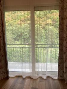 duże okno z białymi zasłonami i balkonem w obiekcie BiancoGelso b&b Vegan w mieście Gardone Riviera