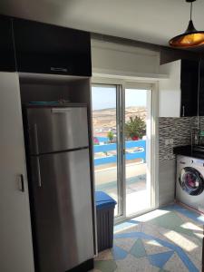 a kitchen with a refrigerator and a view of a yard at Villa Moulay bousselham in Moulay Bousselham