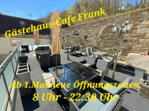 balcón con mesa de cristal, sillas y pared de ladrillo en Gästehaus - Café Frank, en Antweiler