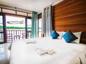 a bedroom with a large white bed with blue pillows at Norn Nab Dao Rimkhong in Chiang Khan