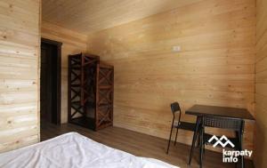 Cette chambre est dotée d'un mur en bois avec une table et une chaise. dans l'établissement Гірка, à Skole