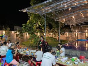 grupa ludzi siedzących przy stolikach jedzących jedzenie w obiekcie Quanho Villa w mieście Bắc Ninh