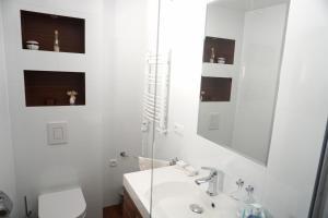 a white bathroom with a sink and a toilet at Apartamenty Leśny Zakątek in Dziemiany