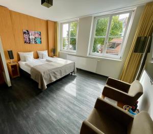 a hotel room with a bed and a chair and two windows at Hotel Hafenresidenz Stralsund in Stralsund