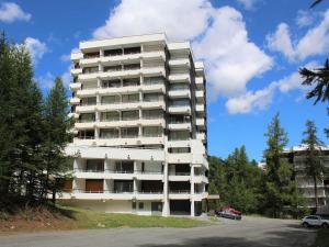 un edificio de apartamentos alto y blanco con aparcamiento en Appartement Vars, 1 pièce, 6 personnes - FR-1-330B-29 en Vars
