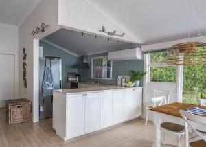 una cucina con mobili bianchi e un tavolo e una sala da pranzo di Tides Reach Boathouse water-access-only a Church Point