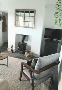 a living room with a chair and a fireplace at Romantic & Cosy Cottage with Direct Access to the Hills in Malvern Wells