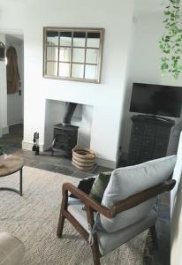 a living room with a chair and a fireplace at Romantic & Cosy Cottage with Direct Access to the Hills in Malvern Wells +32 photos