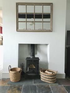 a fireplace with two baskets in front of it at Romantic & Cosy Cottage with Direct Access to the Hills in Malvern Wells