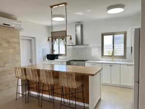 a kitchen with a large wooden island with stools at וילת קסם הזוהר- ניר יפה in Nir Yafe