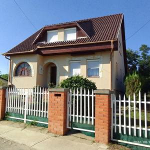 a small house with a white picket fence at István Apartman in Tiszafüred