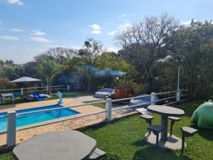 a backyard with a swimming pool and a picnic table and a table at Pousada Sitio Roda D'Água Mairinque in Mairinque
