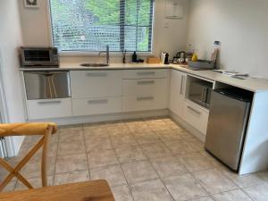 a kitchen with white cabinets and a tile floor at Cosy Cottage in the Vines in Waipara