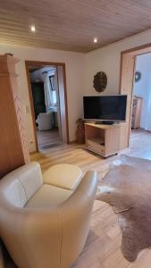 a living room with a white chair and a flat screen tv at Heike Hauswirth KOFELBLICK in Oberammergau