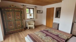 a bedroom with a bed and a cabinet and a chair at Heike Hauswirth KOFELBLICK in Oberammergau
