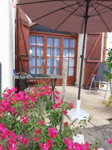 eine Terrasse mit einem Tisch, einem Sonnenschirm und Blumen in der Unterkunft Bompastor in Bompas