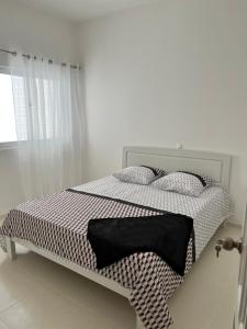 a white bedroom with a bed with a black and white comforter at Super appartement central avec patio. in Santa Maria