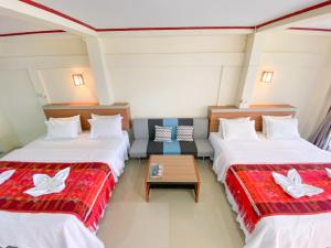 a hotel room with two beds and a couch at Lekjon Cottage in Tuktuk Siadong