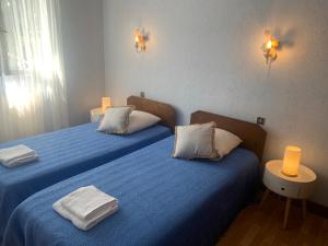 two beds in a room with blue sheets and white pillows at A louer appartement dans une maison in Arcangues