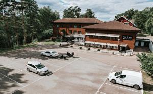 zwei weiße Autos auf einem Parkplatz vor einem Gebäude geparkt in der Unterkunft Nadden Hotell & Konferens in Ramnäs