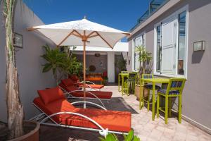 een patio met een tafel en stoelen en een parasol bij Riad Mylaya in Marrakesh