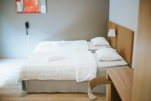 Duas camas num quarto com lençóis e almofadas brancos em Nadden Hotell & Konferens em Ramnäs