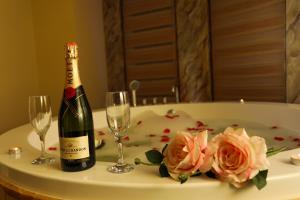 a bottle of champagne and two glasses on a table with roses at Hotel Empire Albania in Durrës