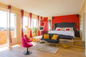een slaapkamer met rode muren en een bed en een bank bij Le Boudoir de Fanny - Sauna/Balnéo/ciné/Hamacs in Le Havre
