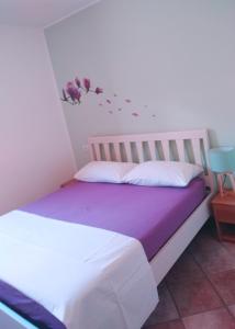 Cama blanca con sábanas púrpuras y flores en la pared en Green Nest, en Farra di Soligo