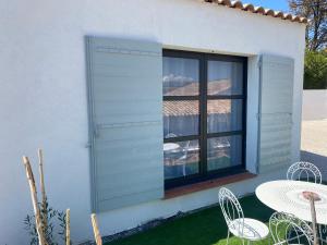 d'une terrasse avec une table, des chaises et une fenêtre. dans l'établissement Maison avec vue sur le massif de l Étoile, à Marseille