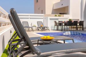 a patio with chairs and a table and a pool at Protaras Sol e Mar Villa 3 in Protaras