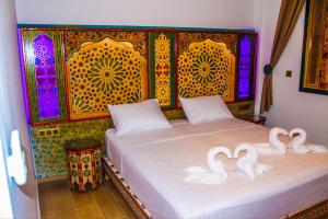 two swans are sitting on a bed in a room at Riad Azemmat in Chefchaouene