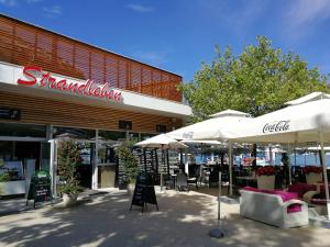 een winkel met tafels en parasols ervoor bij Cityapartment am See in Pörtschach am Wörthersee