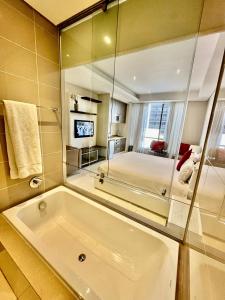 a large bathroom with a tub and a bedroom at A cozy apartment at Sandton Skye in Johannesburg