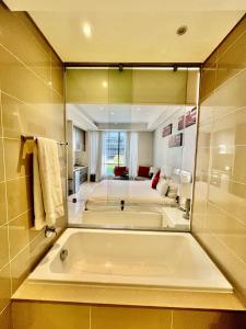 a large bathroom with a tub and a large mirror at A cozy apartment at Sandton Skye in Johannesburg