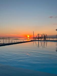 a swimming pool with the sunset in the background at Laguna Faro Suites - Adults Only & Free Beach in Grado