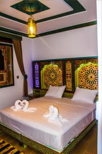 ein Schlafzimmer mit zwei Schwänen in Handtüchern auf einem Bett in der Unterkunft Riad Azemmat in Chefchaouen