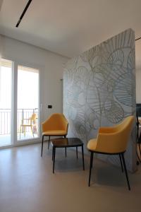 duas cadeiras e uma mesa num quarto com uma parede em B&B Le Suites di Costanza em Cefalù