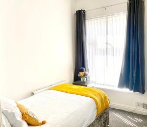 a bedroom with a bed with a yellow blanket and a window at Cosy Cheerful 2 Beds Near Piccadilly, Etihad Stadium Sleeps upto 5 in Manchester