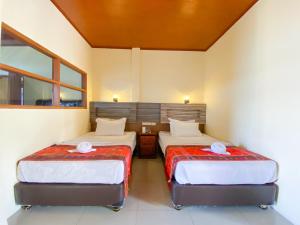 two beds in a room with two bedsitures at Lekjon Cottage in Tuktuk Siadong