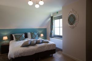 a bedroom with a bed with pillows and a window at Cottage d'Hoge Schure in Heuvelland