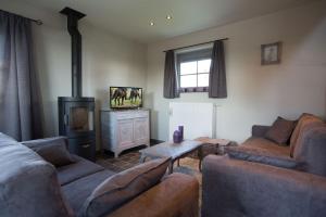 sala de estar con 2 sofás y TV en Cottage d'Hoge Schure, en Heuvelland