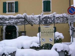 a building covered in snow with signs in front of it at LOCANDA SAN GALLO in Moggio Udinese