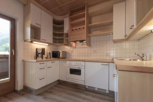 una cocina con armarios blancos y fregadero en Flo's Apartment, en Grossarl