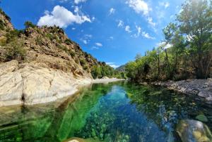 a river in the middle of a rocky canyon at Pianotolinca in Moltifao